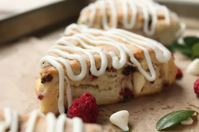 a close up of a pastry with icing and raspberries